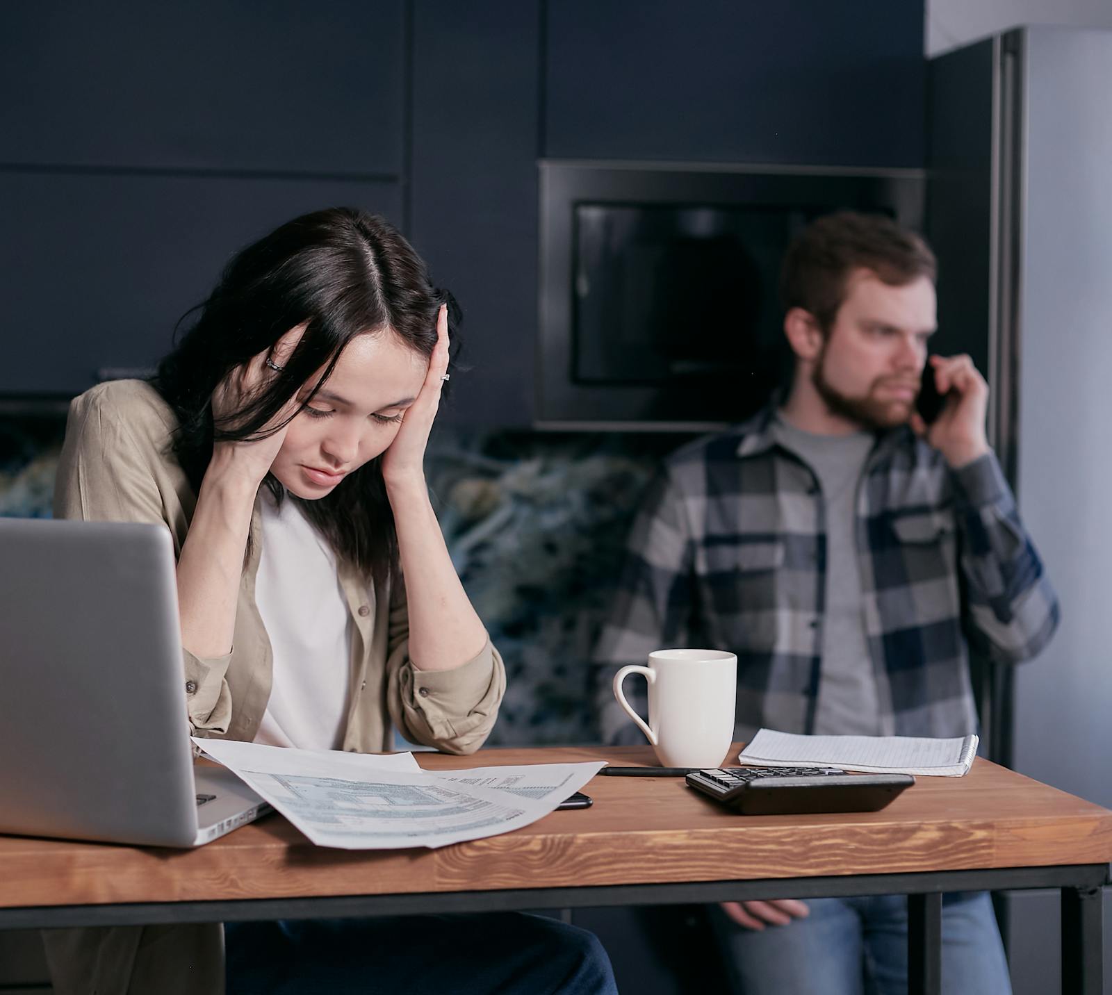 Stressed person reviewing paperwork and laptop data